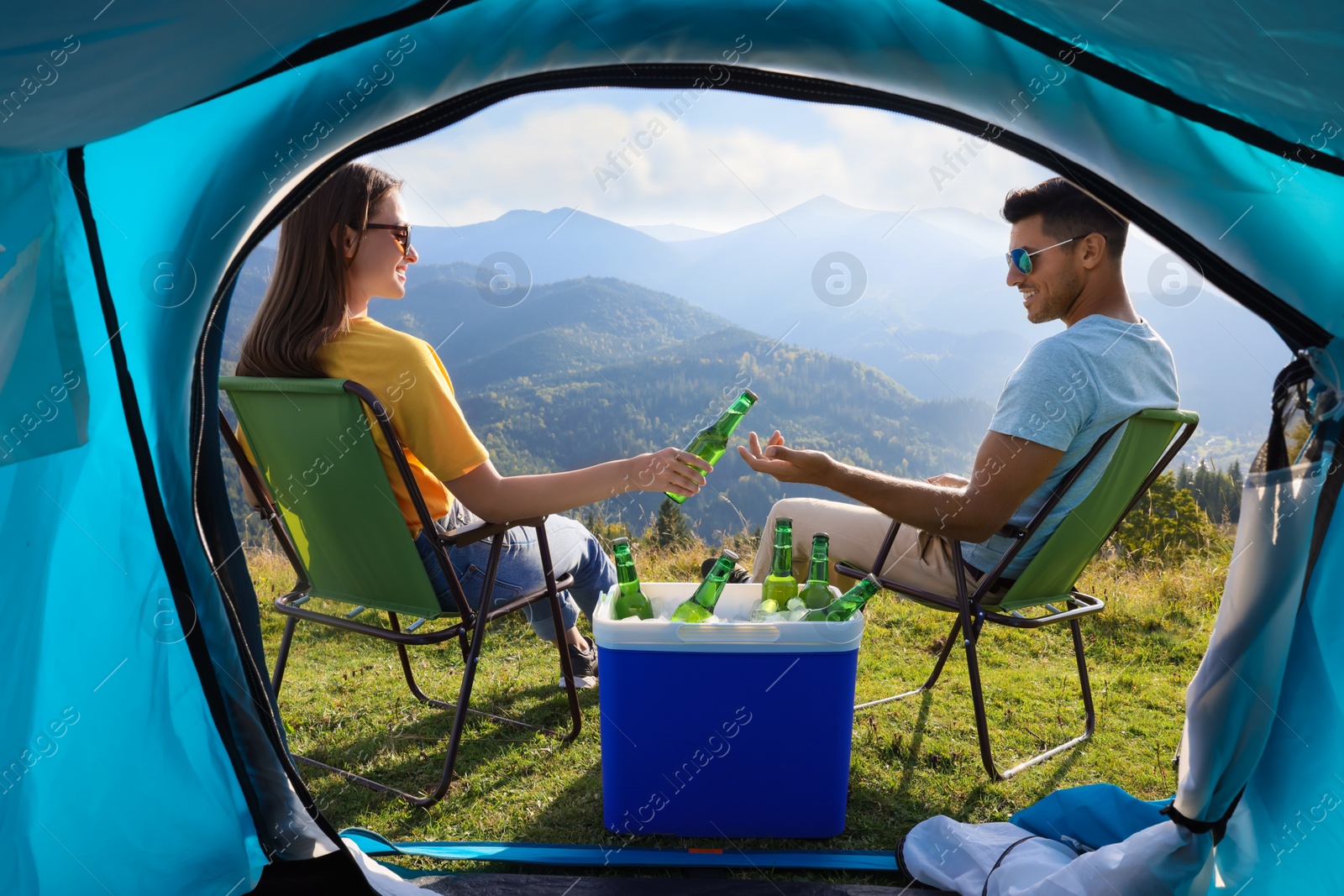 Photo of Couple and cool box with bottles of beer in mountains, view from tent