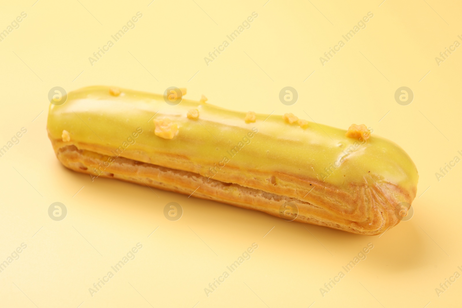 Photo of Delicious eclair covered with glaze on yellow background