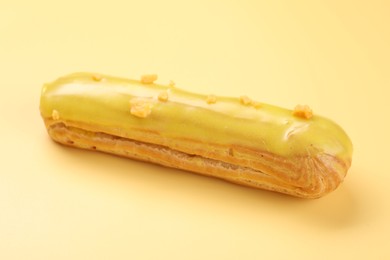 Delicious eclair covered with glaze on yellow background