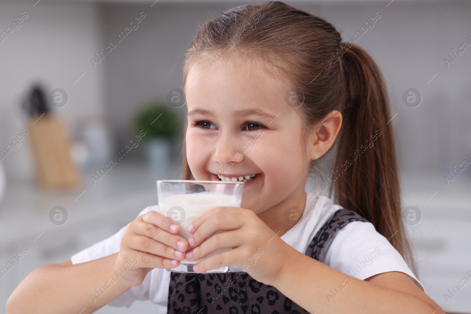 Photo of Cute girl with glass of fresh milk indoors