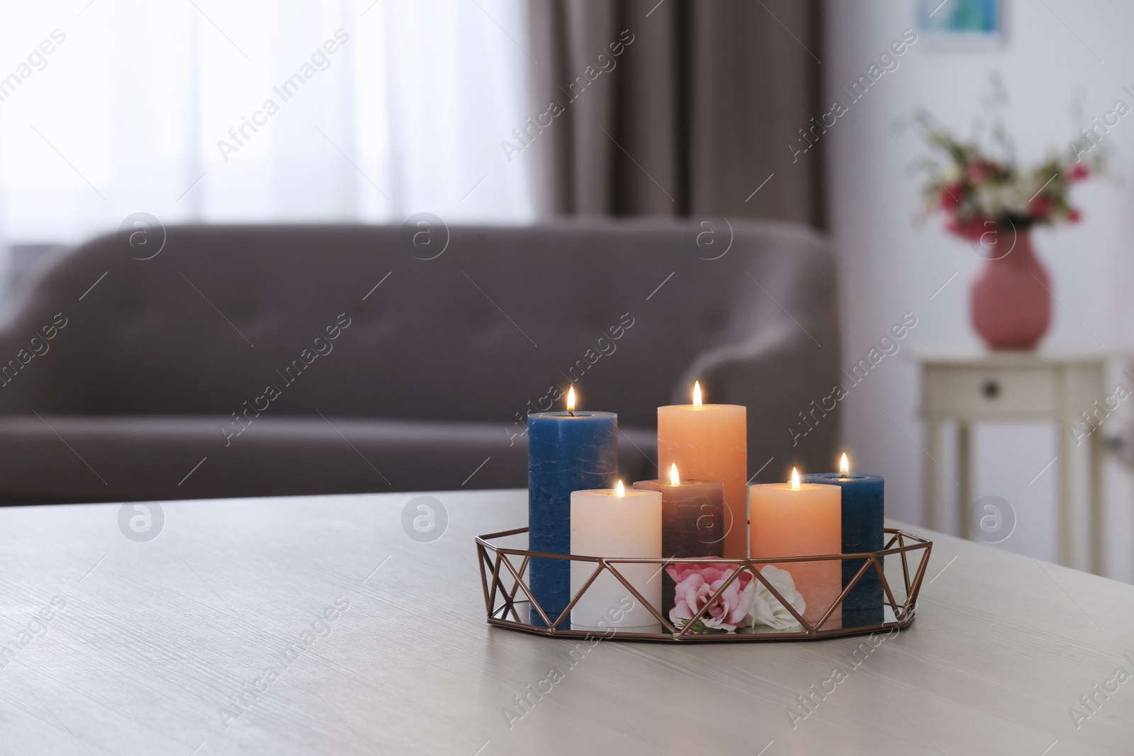 Photo of Tray with burning candles and flowers on table in living room. Space for text