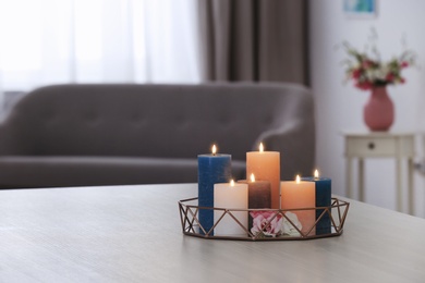 Tray with burning candles and flowers on table in living room. Space for text