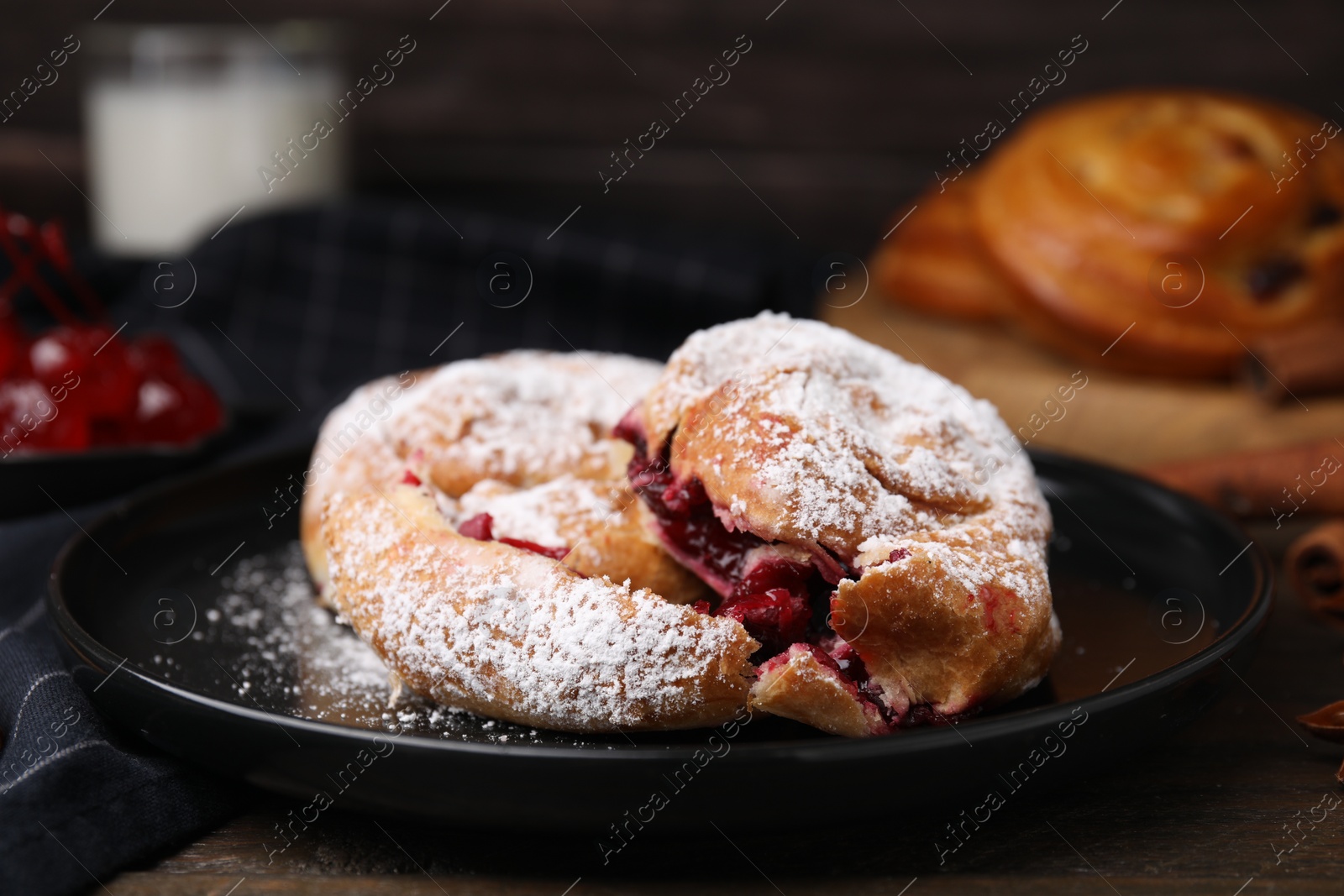 Photo of Delicious buns with berries and sugar powder on table, closeup