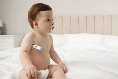 Photo of Adorable baby with thermometer indoors. Measuring temperature