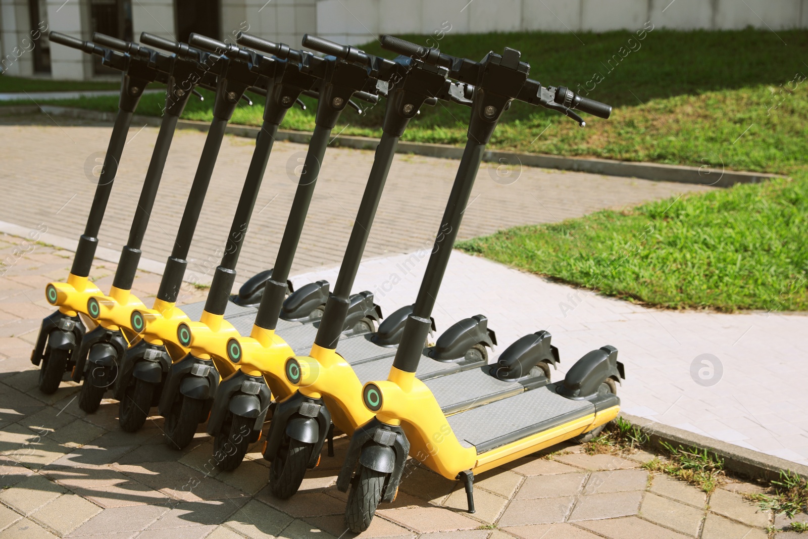 Photo of Many modern electric scooters on city street. Rental service