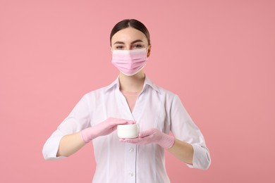 Photo of Cosmetologist with cosmetic product on pink background