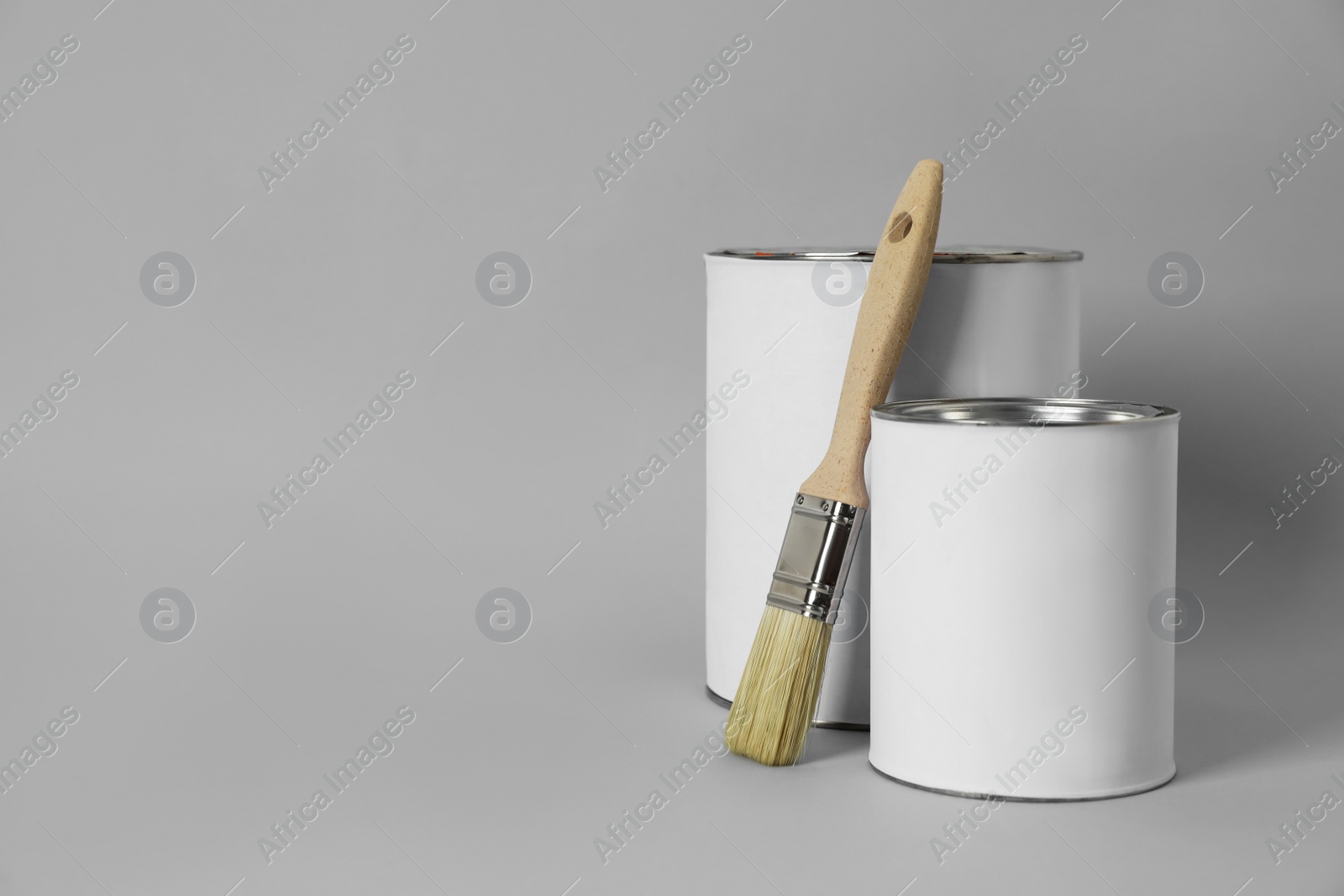 Photo of Cans of orange paint and brush on grey background. Space for text