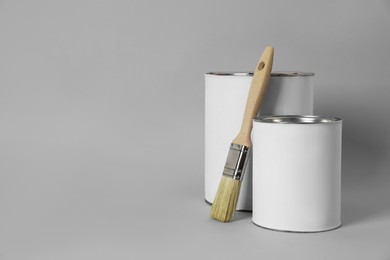 Photo of Cans of orange paint and brush on grey background. Space for text