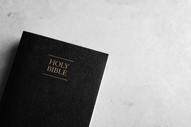 Photo of Bible on light gray table, top view with space for text. Christian religious book