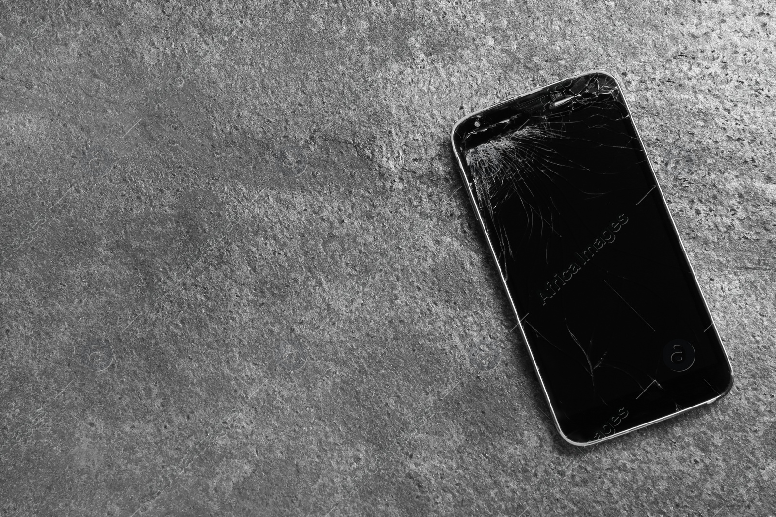 Photo of Damaged smartphone on grey table, top view with space for text. Device repairing