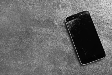 Damaged smartphone on grey table, top view with space for text. Device repairing