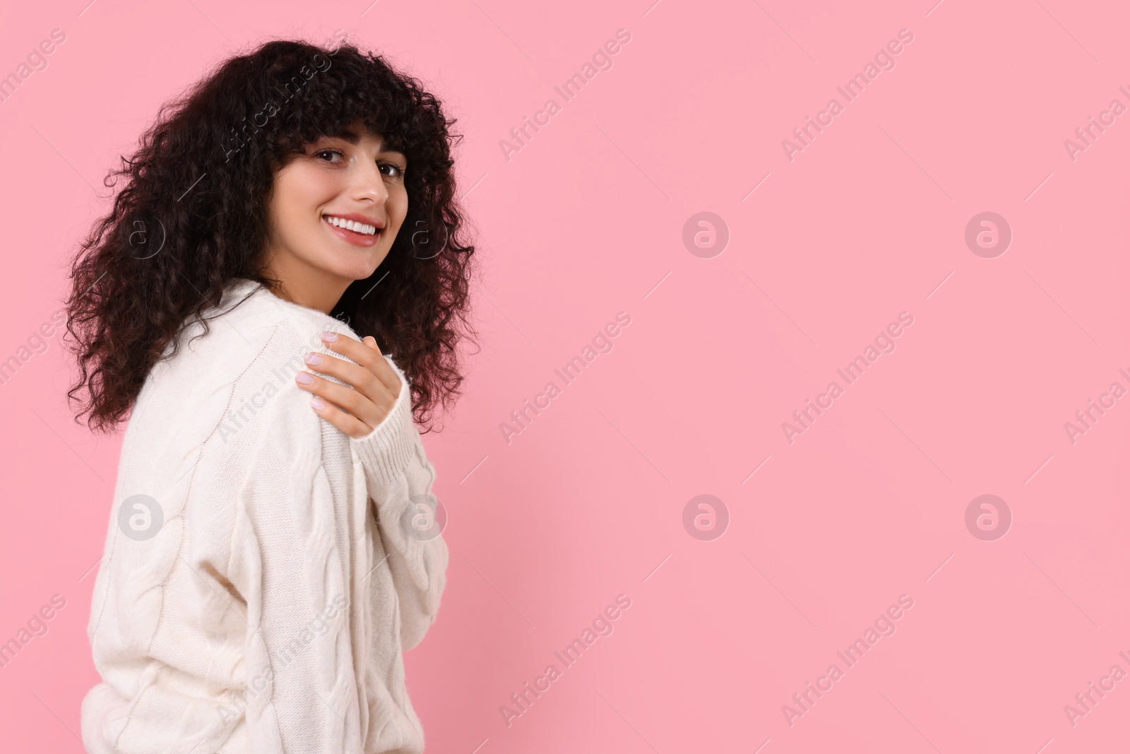 Photo of Happy young woman in stylish white sweater on pink background, space for text