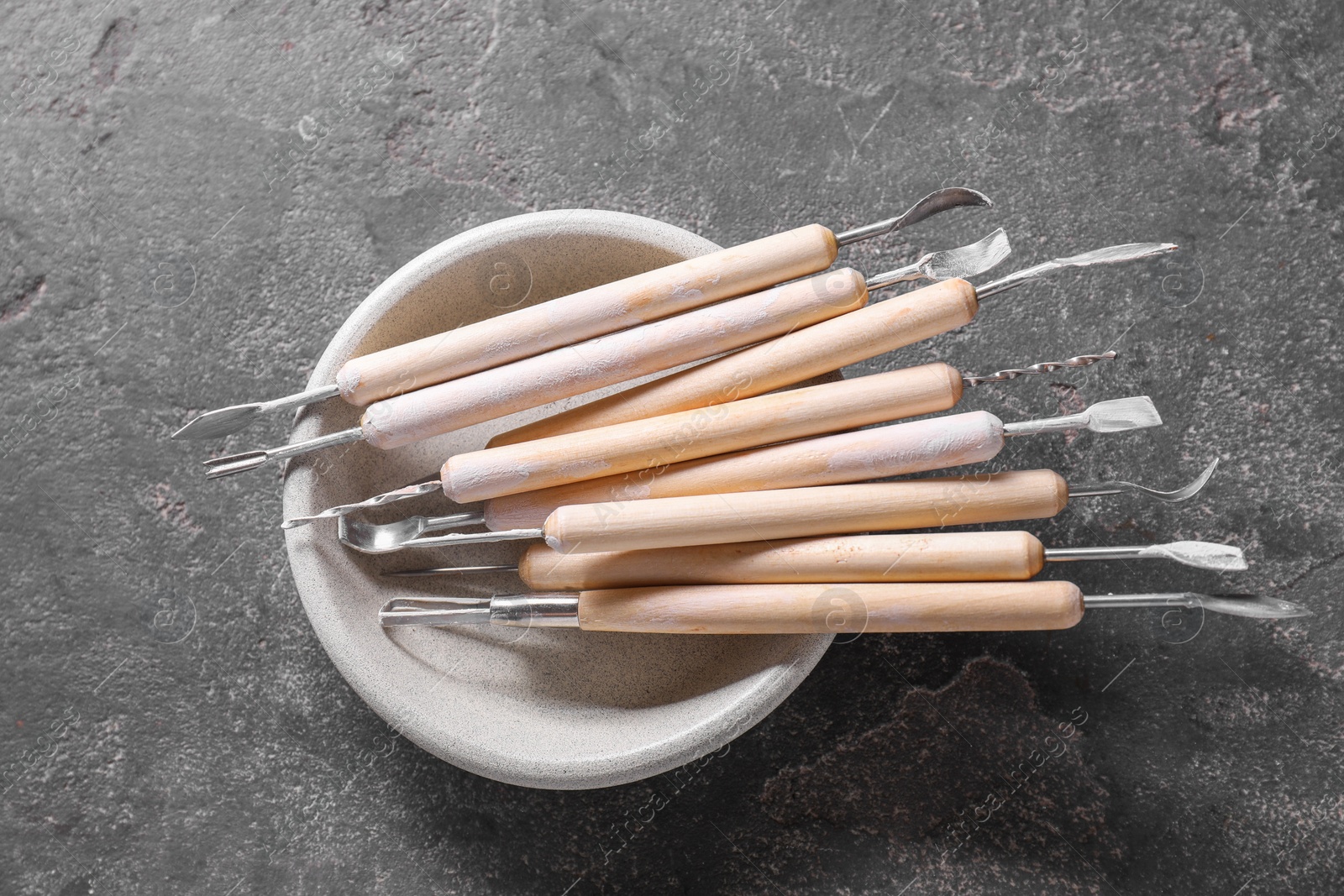 Photo of Set of different clay crafting tools on grey table, top view