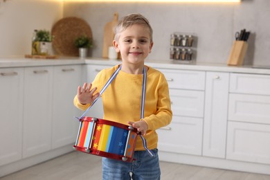 Little boy playing toy drum in kitchen