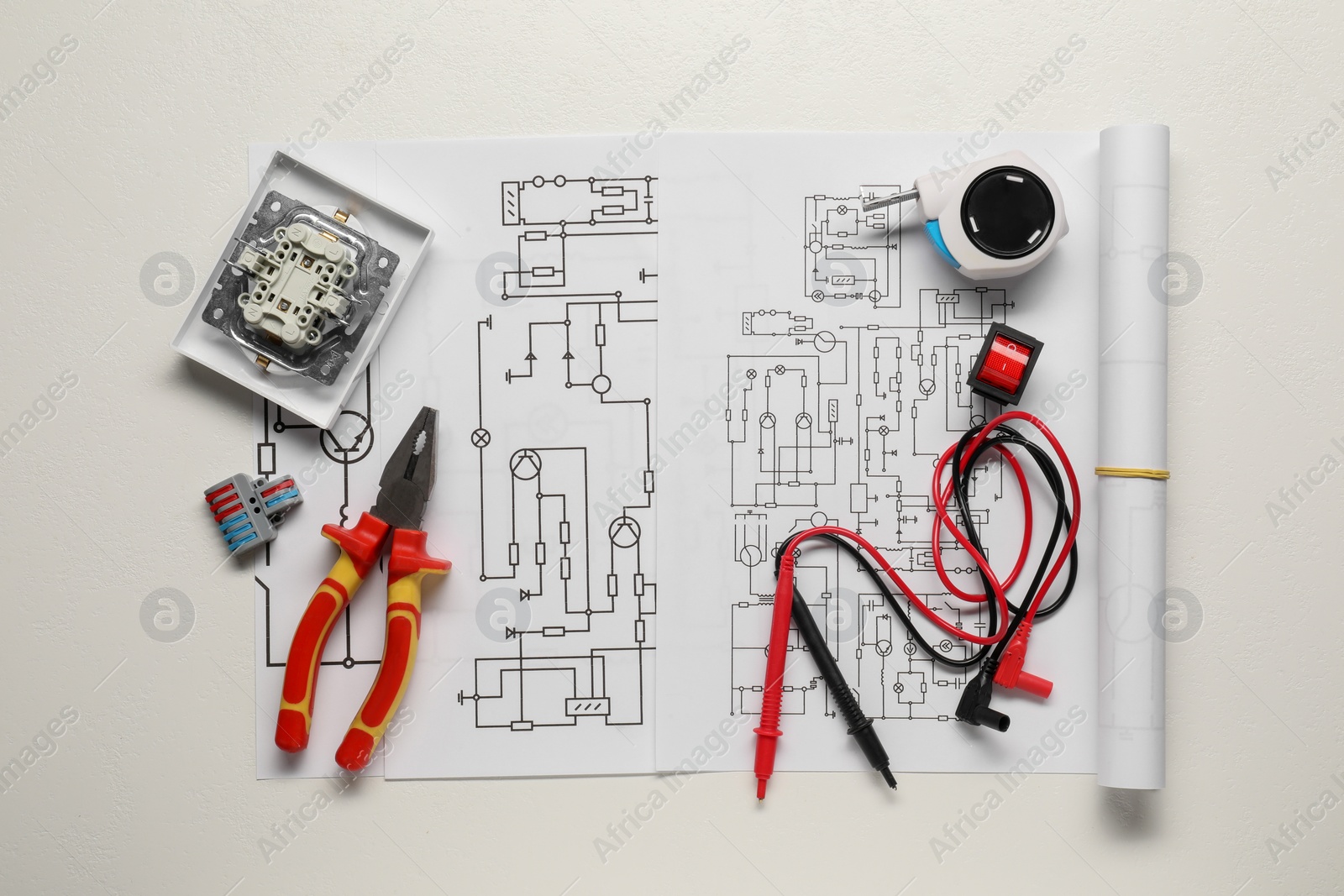 Photo of Wiring diagrams, different electrician's equipment and pliers on white background, top view