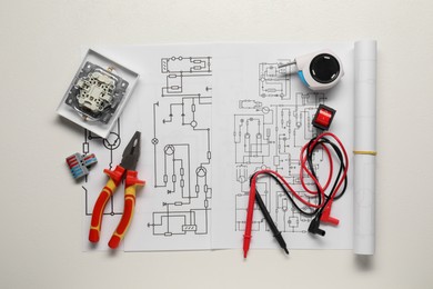 Wiring diagrams, different electrician's equipment and pliers on white background, top view