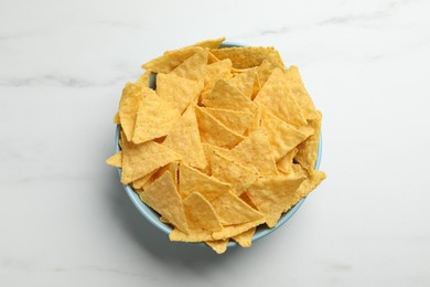Photo of Tortilla chips (nachos) in bowl on white table, top view