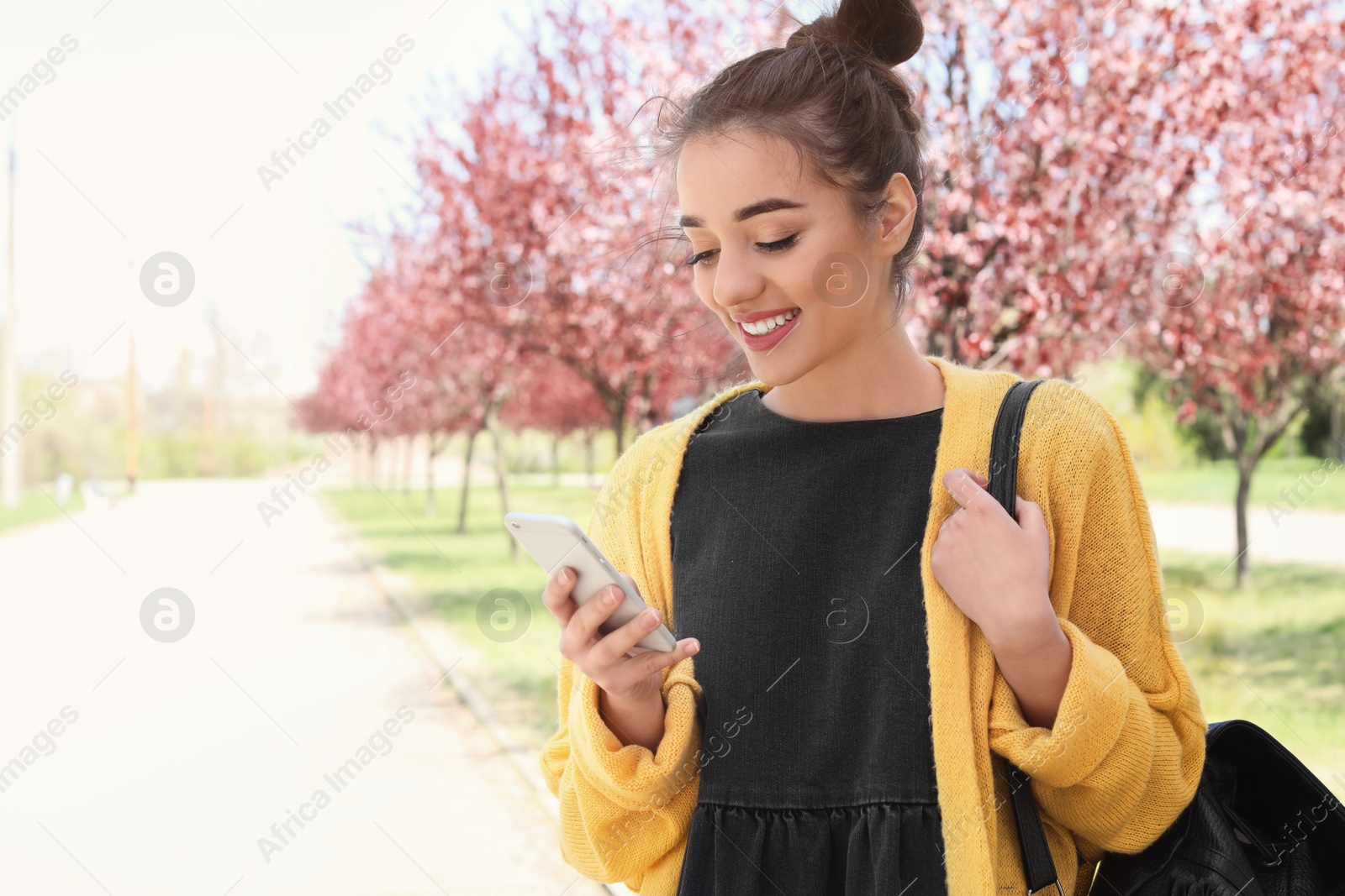 Photo of Young woman using phone outdoors on sunny day