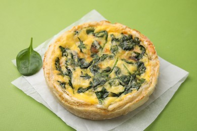 Photo of Delicious pie with spinach on green background, closeup