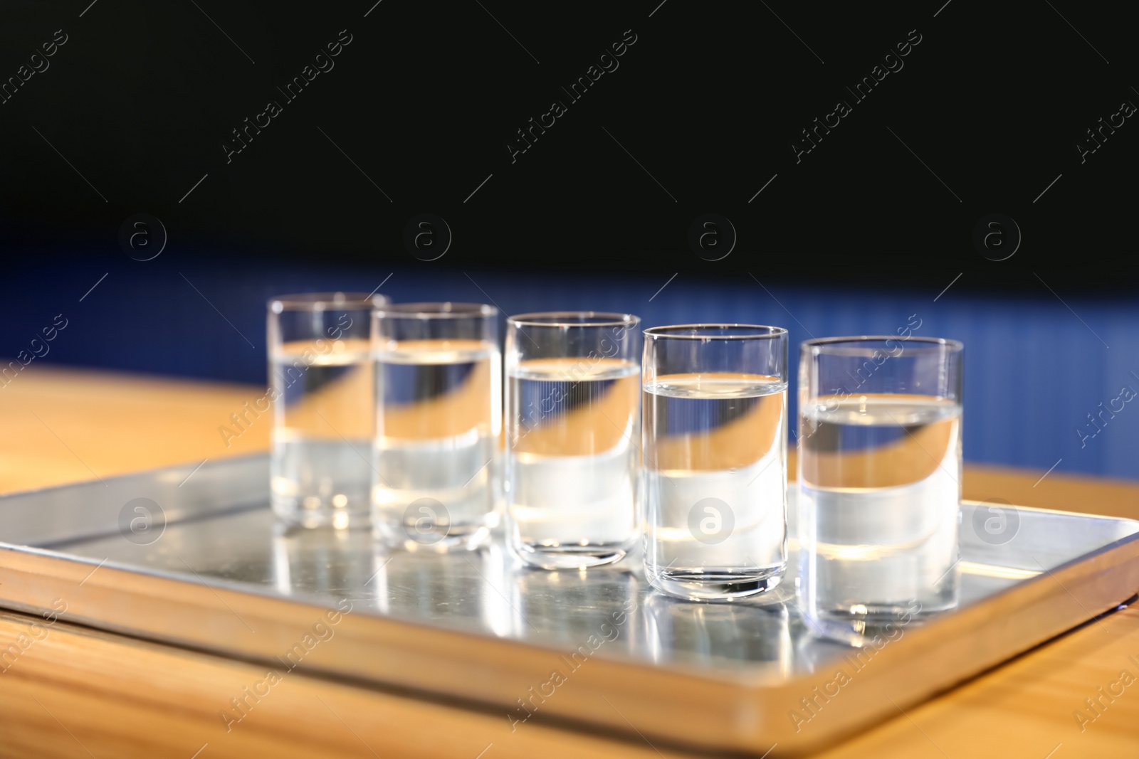 Photo of Shots of vodka on bar counter against dark background