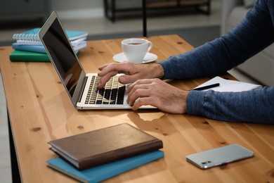 Photo of Man with laptop learning at wooden table indoors, closeup