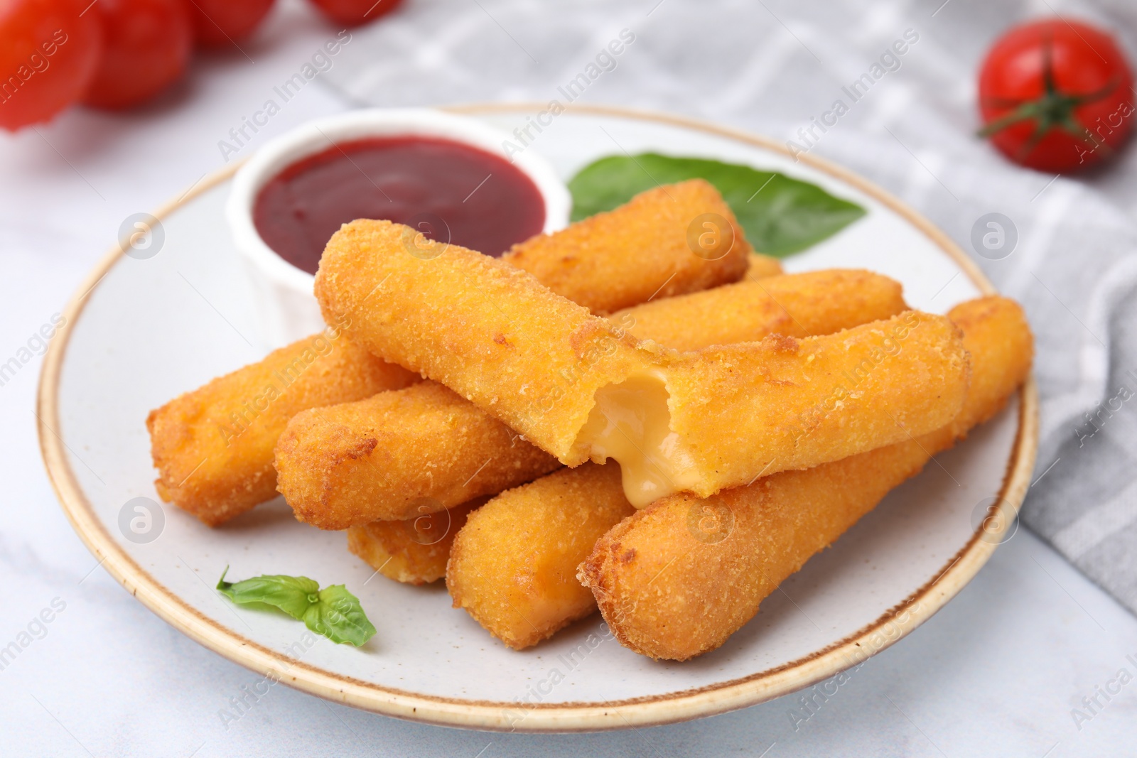 Photo of Tasty fried mozzarella sticks served with tomato sauce on white table