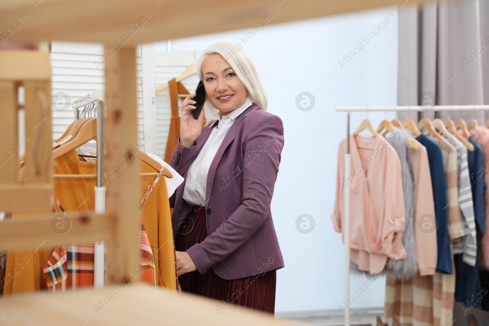 Photo of Female business owner talking on phone in boutique