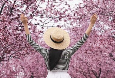 Young woman in park with blooming trees. Spring look