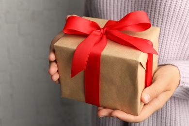 Photo of Young woman holding Christmas gift on light background, closeup