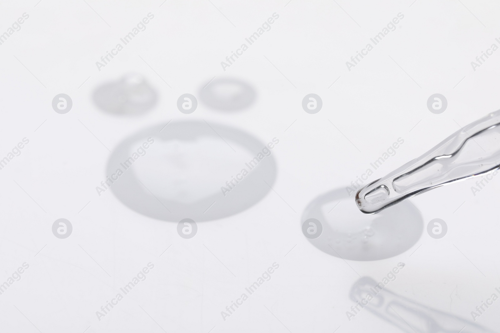 Photo of Glass pipette and transparent liquid on white background, closeup