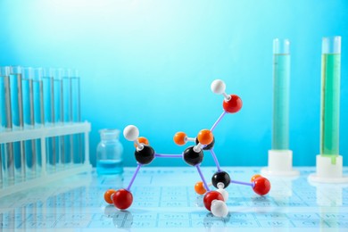 Photo of Molecular model and laboratory glassware against light blue background