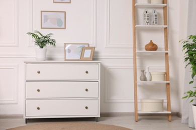 Picture frames hanging on white wall and chest of drawers at home