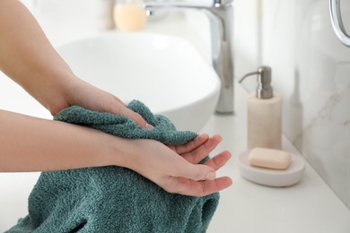 Photo of Woman wiping hands with towel in bathroom, closeup