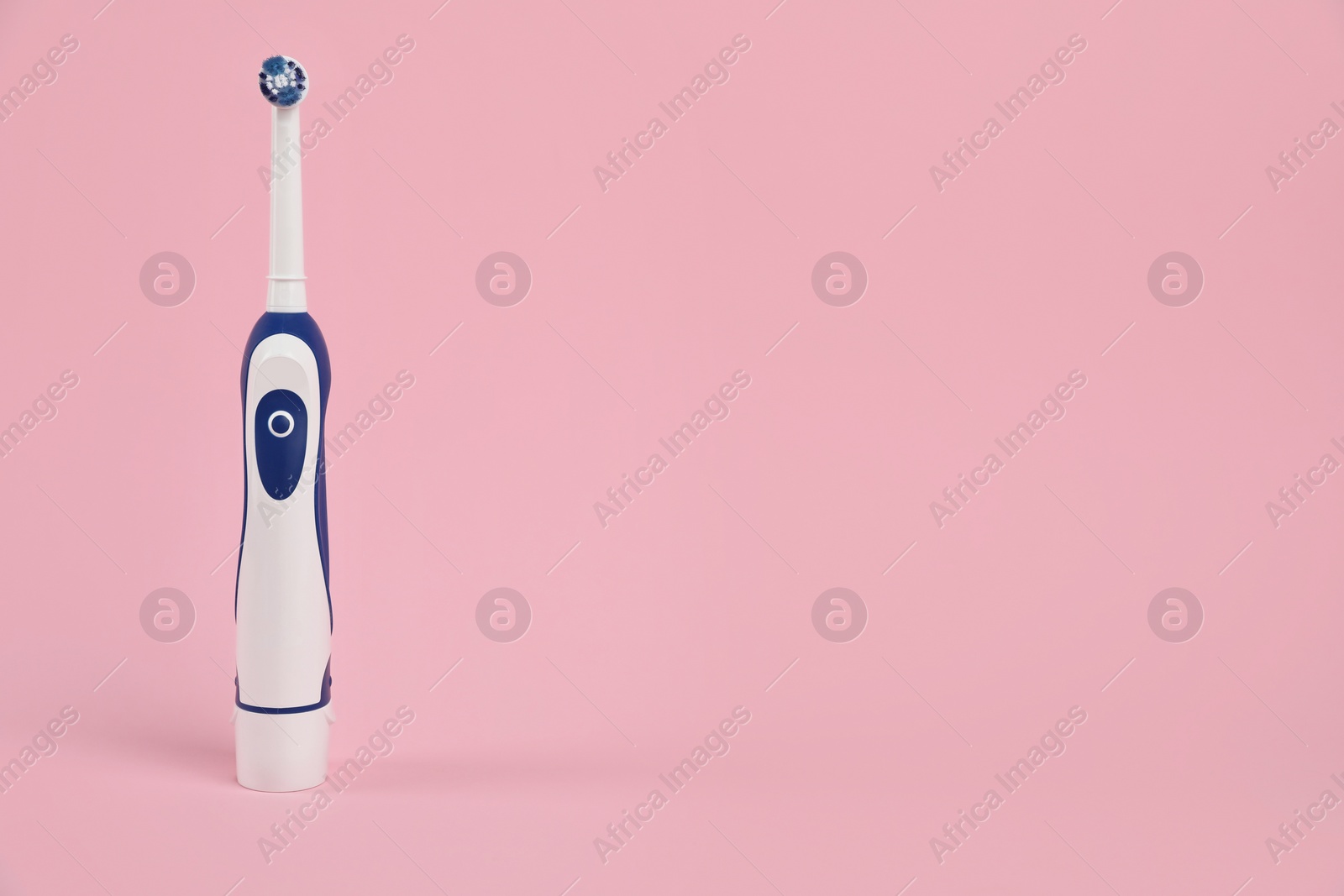 Photo of Electric toothbrush on pink background, space for text