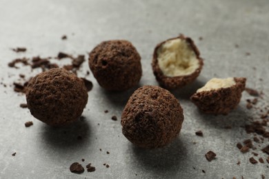 Many delicious chocolate truffles on grey table