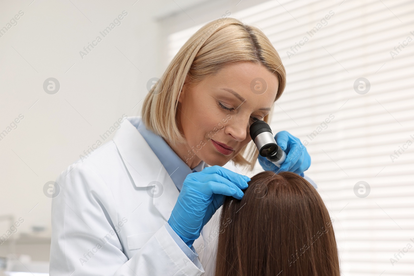 Photo of Trichologist with dermatoscope examining patient`s hair in clinic