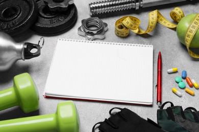 Photo of Notebook, apple and sports equipment on grey textured table. Personal training