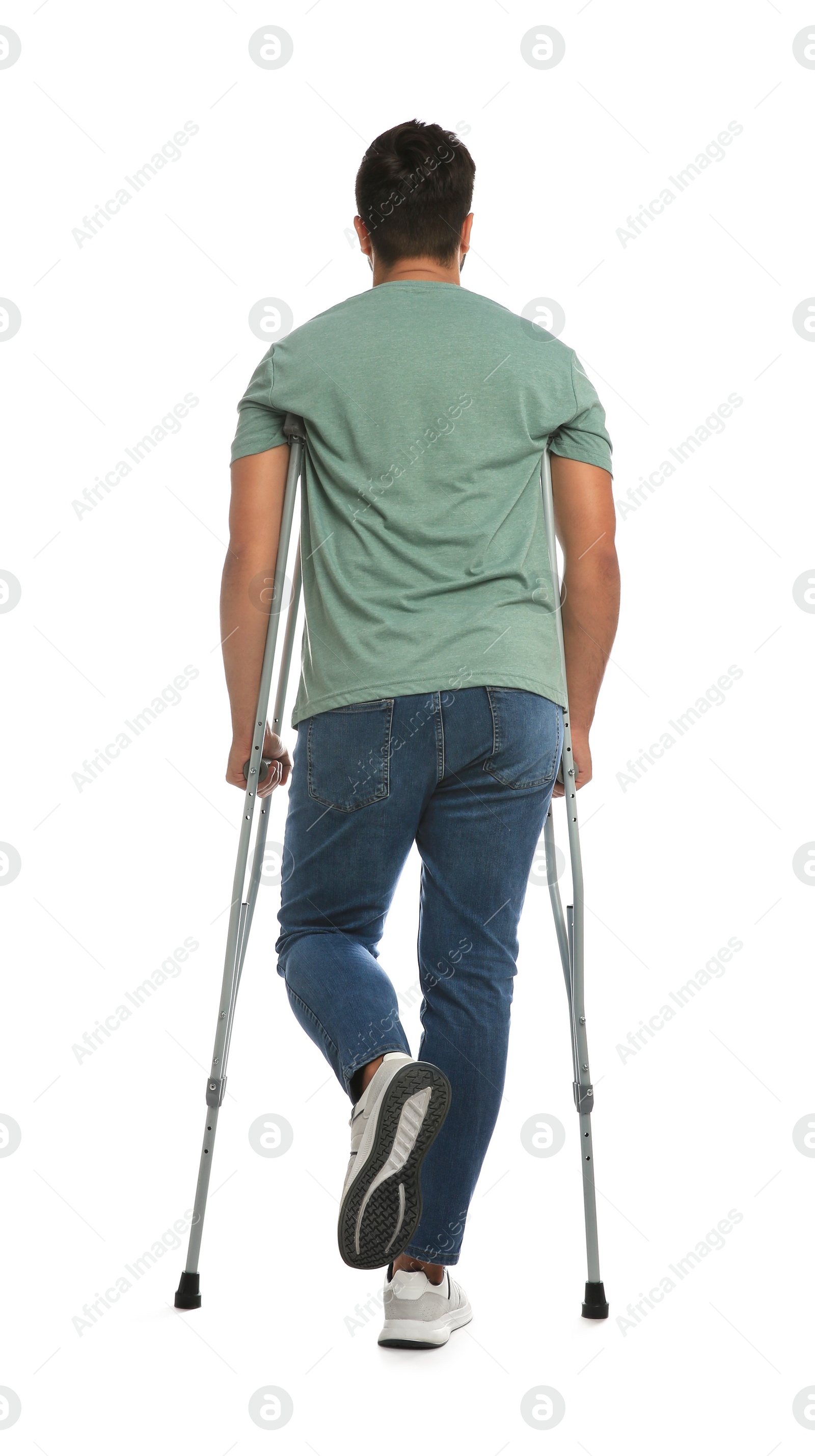 Photo of Young man with axillary crutches on white background, back view