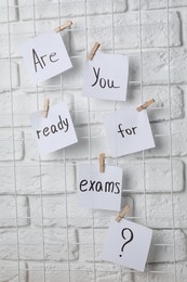 Notes with words Are you ready for exams hanging on white brick wall