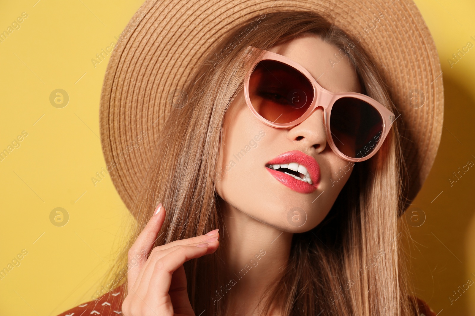 Photo of Young woman wearing stylish sunglasses and hat on yellow background