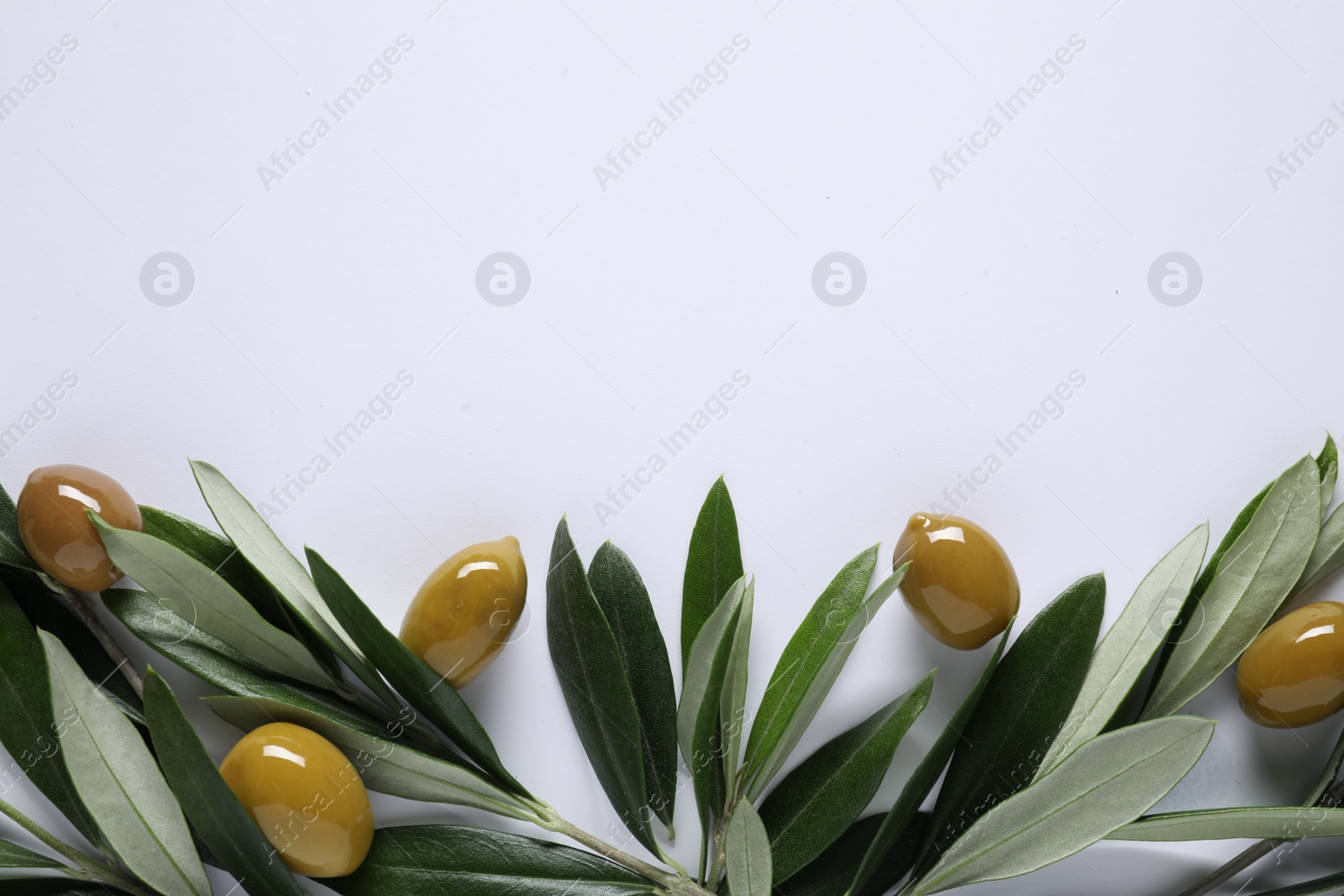 Photo of Fresh green olives and leaves on white background, flat lay. Space for text