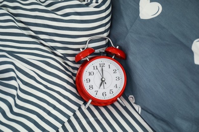 Analog alarm clock on bed, top view. Time of day