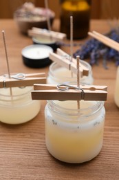 Photo of Glass jars with wax on wooden table. Handmade candles