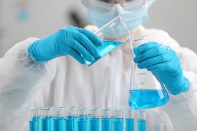 Scientist pouring sample into flask in laboratory, closeup