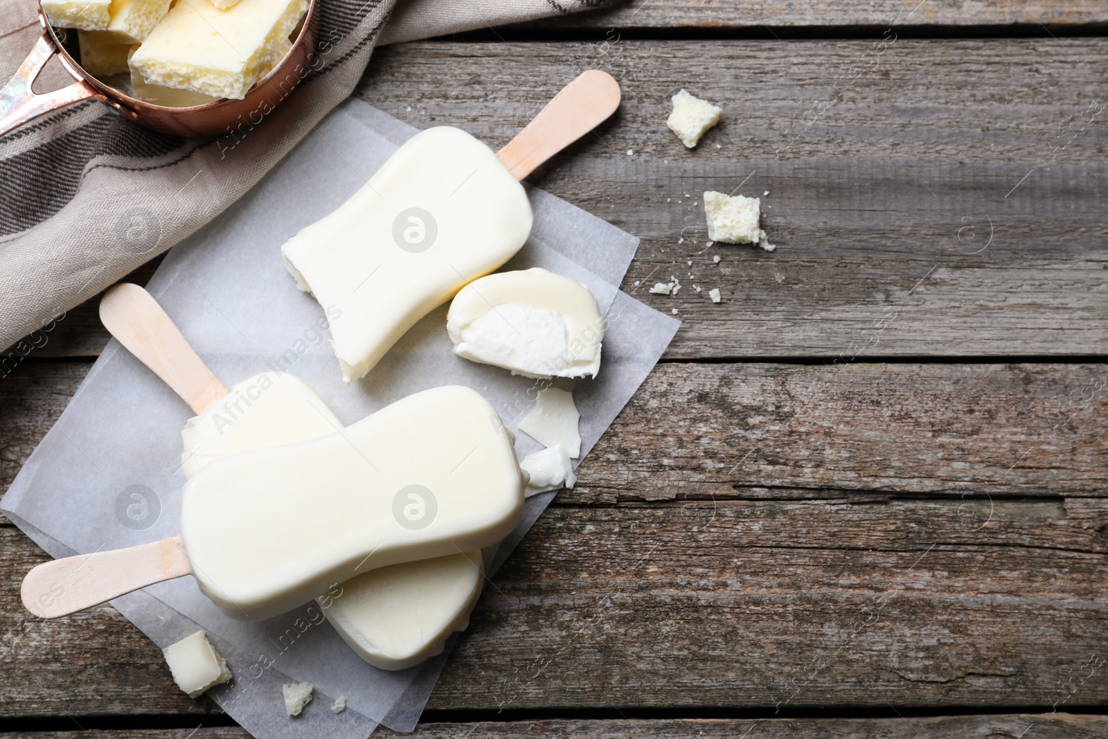 Photo of Delicious glazed ice cream bars on wooden table, flat lay. Space for text