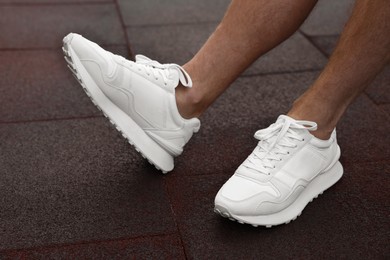 Photo of Man wearing pair of stylish sneakers outdoors, closeup