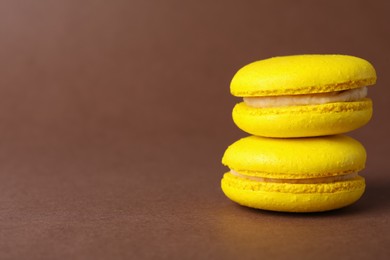Delicious yellow macarons on brown background, closeup. Space for text
