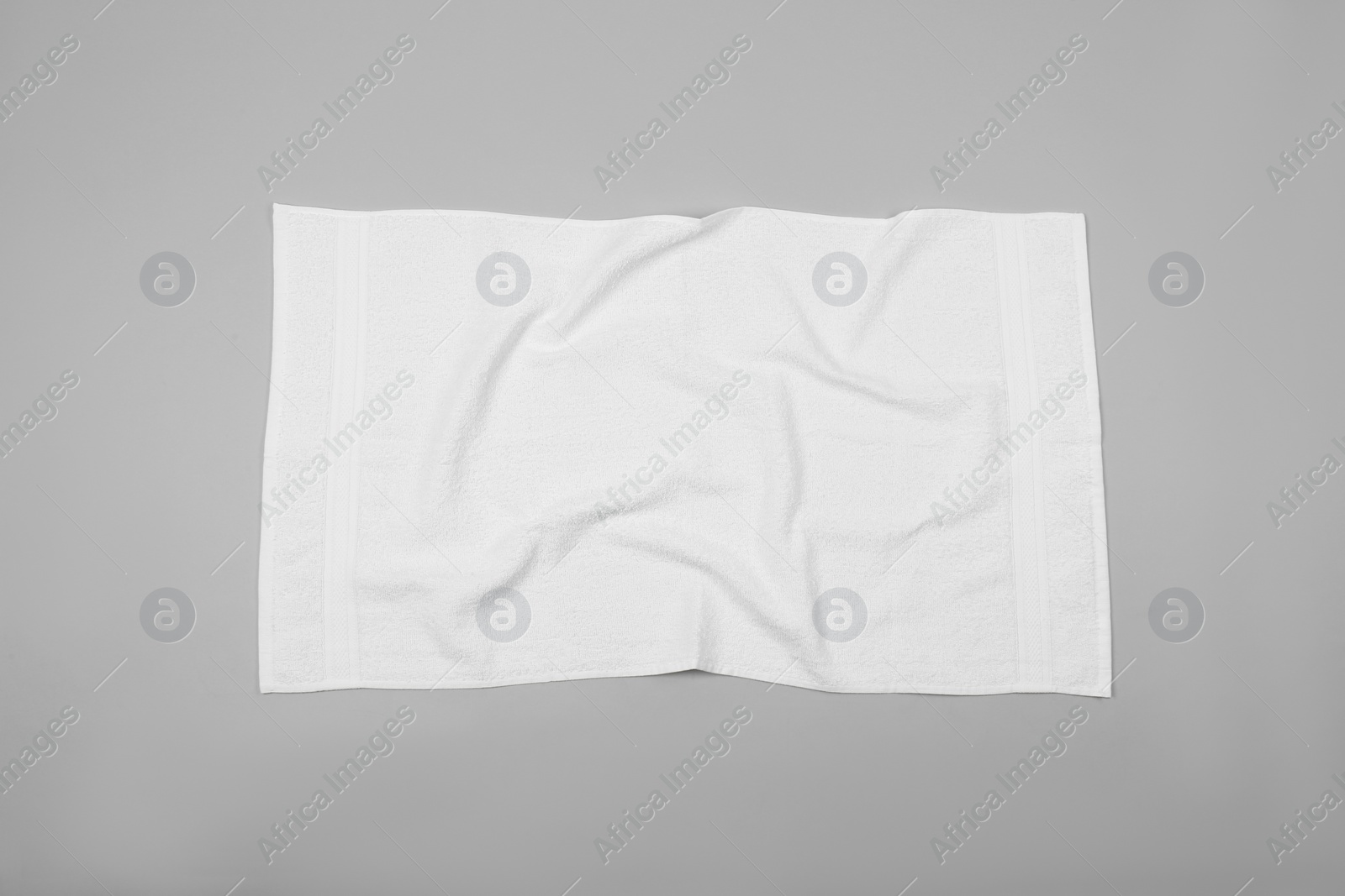 Photo of Crumpled white beach towel on light grey background, top view