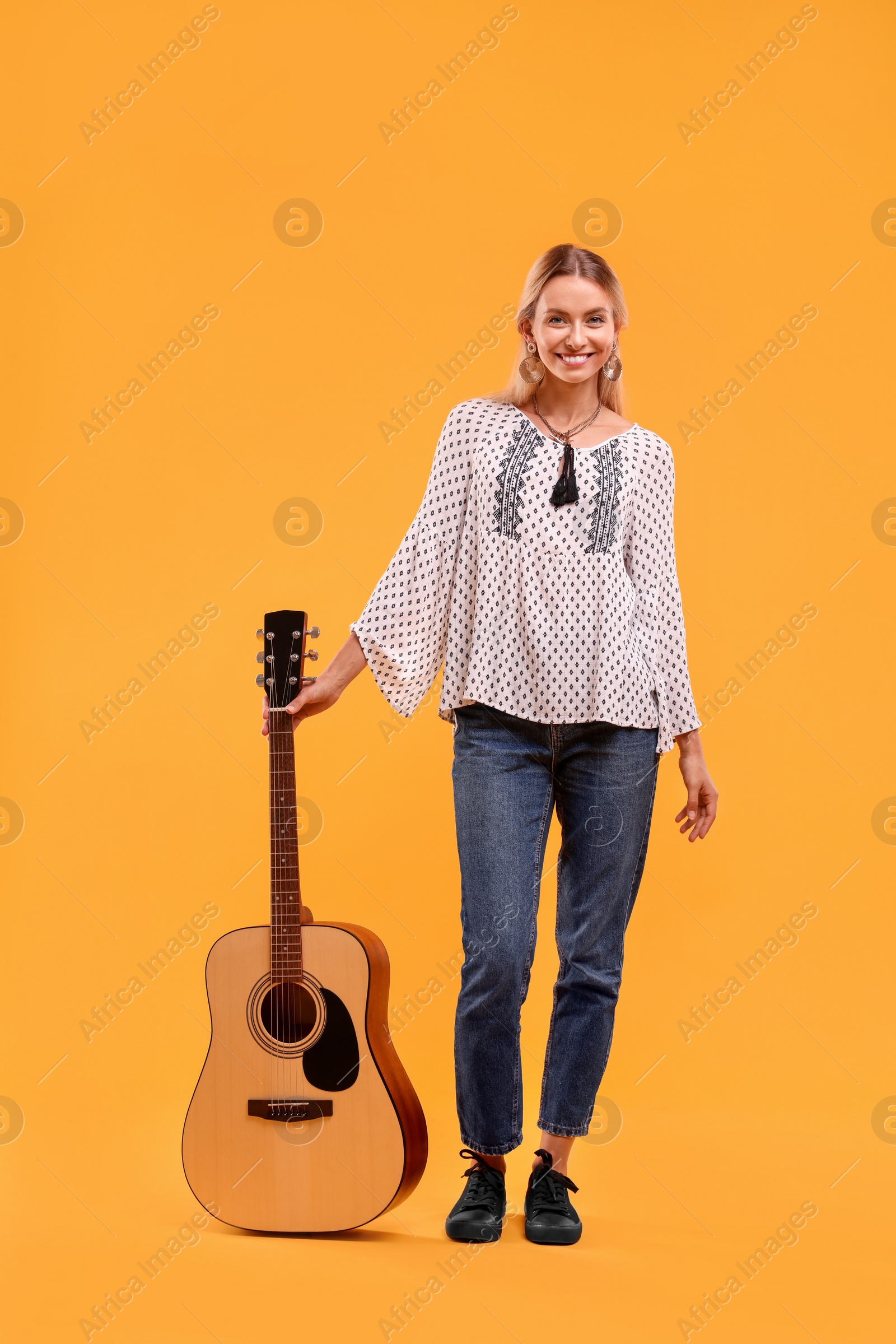 Photo of Happy hippie woman with guitar on yellow background