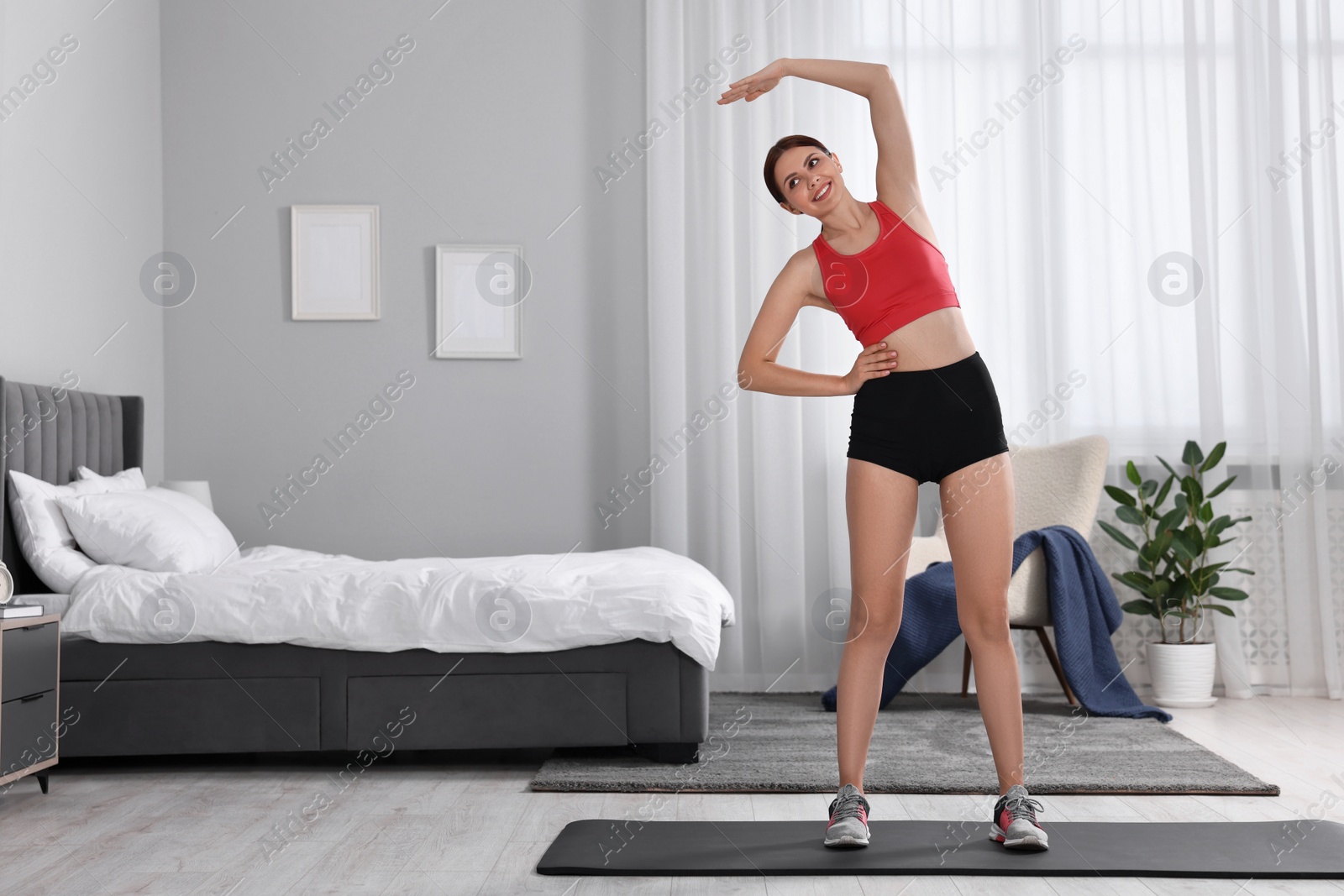 Photo of Morning routine. Happy woman doing stretching exercise at home. Space for text